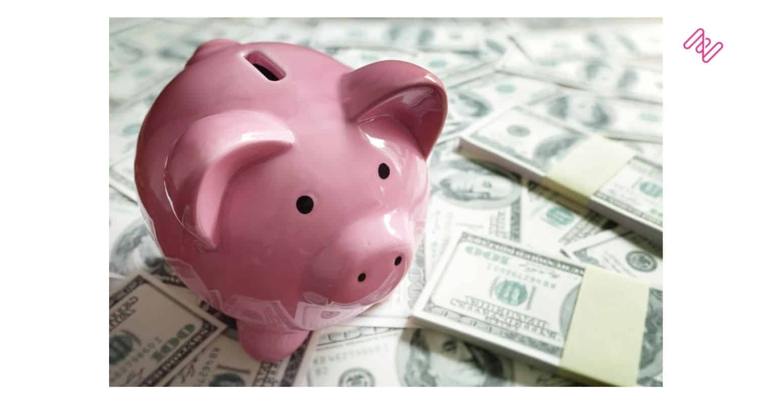 Imagem de um cofre de porquinho ao redor de notas de dóllar representando o faturamento das empresas no cenário low-code com a economia em TI.