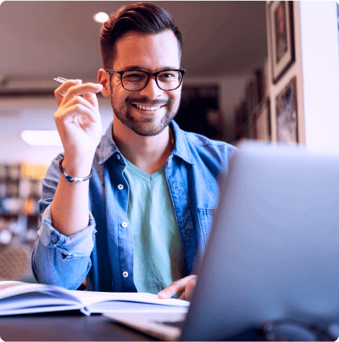 Homem sorrindo em seu espaço de trabalho enquanto mexe no computador em seu Software para workflows automatizados