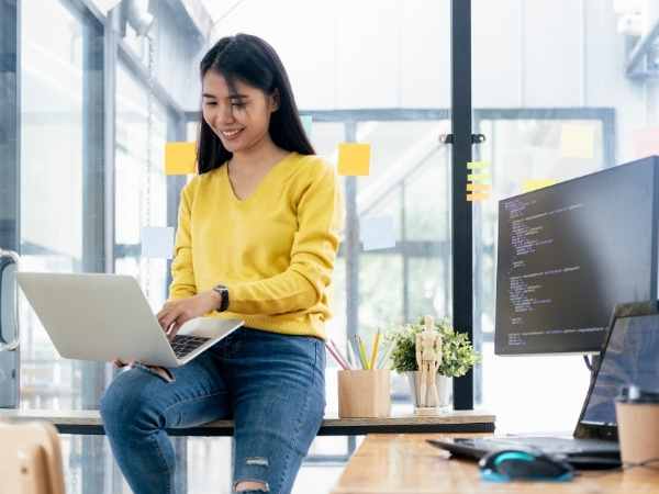 Mulher com computador com mais produtividade com Software low-code para workflows automatizados